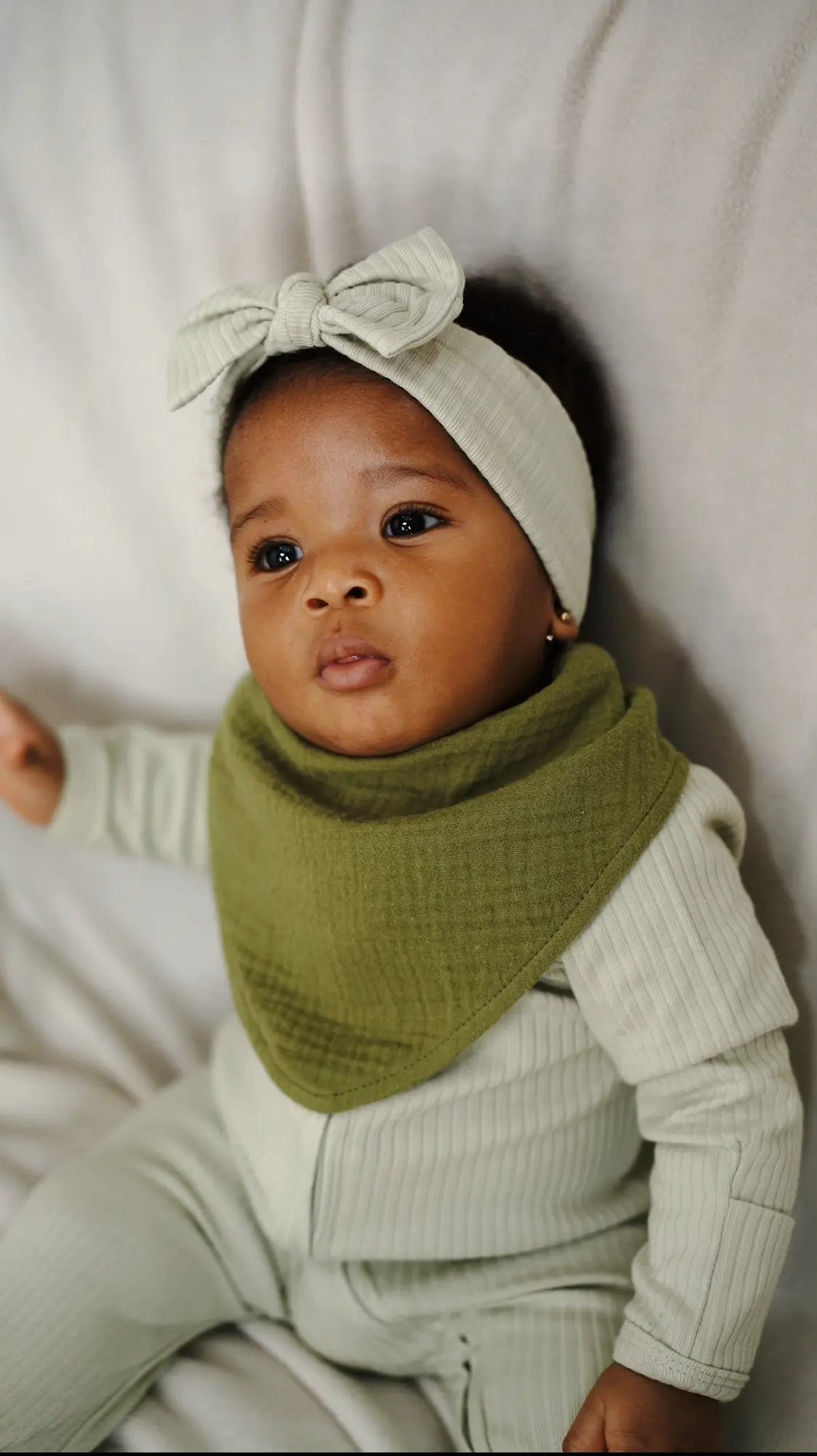 Paalm Baby drea organic cotton bandana bibs set on a baby wearing the Ira Sleepsuit Nigeria