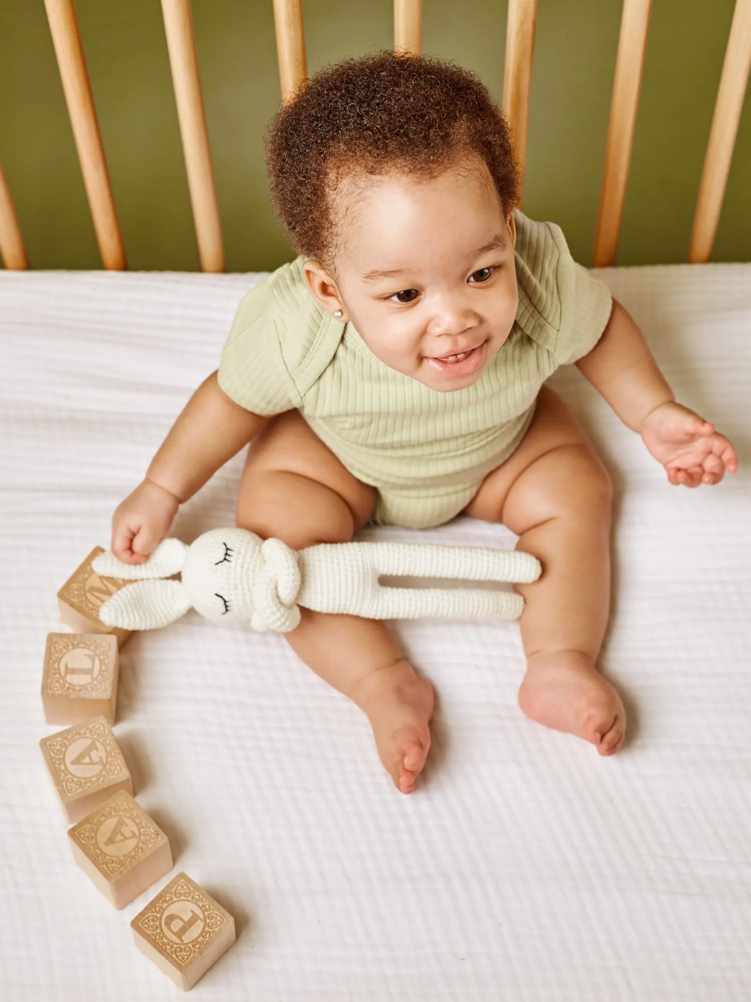 Ari organic ribbed baby bodysuit onesie - lead-free snaps pistachio on baby playing in crib | Paalm Baby Clothing Nigeria